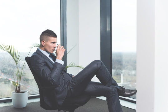 Young modern businessman looking through window in his office