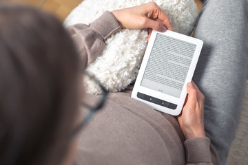 Woman reading an e-book. Digital tablet device in the hands, top view.