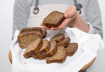 Black rye whole grain bread in the hands of a woman baker. 