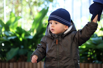 Baby Boy Wearing A Blue Knit Winter Hat And Green Winter Parka