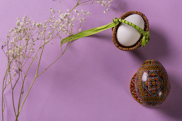 White egg in basket and wooden egg on plate on purple background