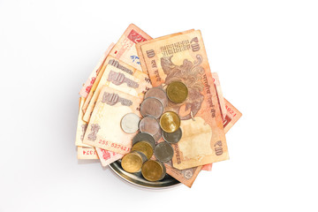 Close up view of donation plate with indian banknotes and coins on white background.