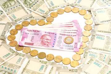 Close up view of new indian 500 and 2000 rupees banknotes and coins. Heartshape concept.