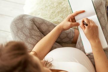 Pregnant woman is getting ready for the maternity hospital, packing baby stuff. Pregnancy, birth concept.