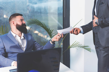 Cheerful boss giving paper to his employee