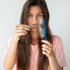 Young woman is upset because of hair loss
