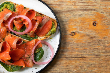 Delicious toasts with smoked salmon, avocado and basil leaves