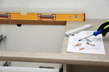 Pracownik pokazuje śrubokrętem na rysunku technicznym do montarzu mebli. - obrazy, fototapety, plakaty