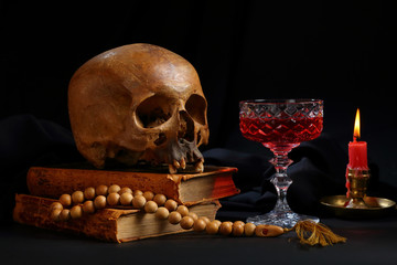 A skull, a rosary, a glass of wine and a burning candle