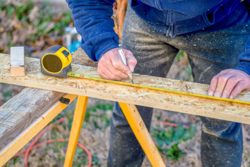 Carpenter measuring materail to be cut for wood project.