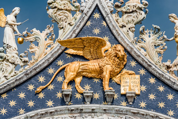 Golden winged lion with parchment as roof decoration of Basilica San Marco in Venice, Italy, summer...
