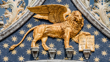Golden winged lion with parchment as roof decoration of Basilica San Marco in Venice, Italy, summer...