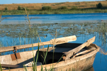 Naklejka premium Boat on the river near the shore. Sunny day, flat river in summer.