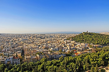 View from Acropolis hill of the city of Athens and the Monument of Philopappos on Musaios hill in Athens, Greece.