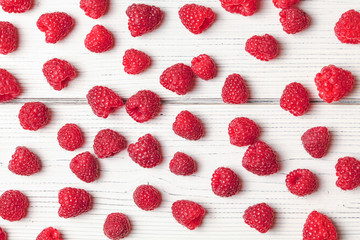 Tabletop view - raspberries scattered on white boards.