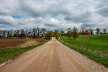 country gravel road with old and broken asphalt