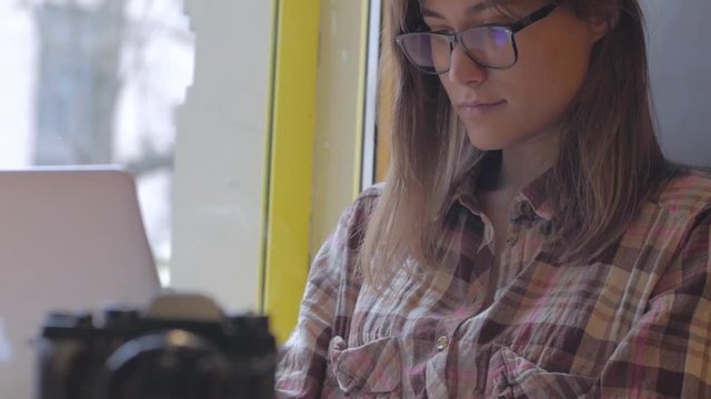 Young woman in glasses work with laptop in the coffee shop