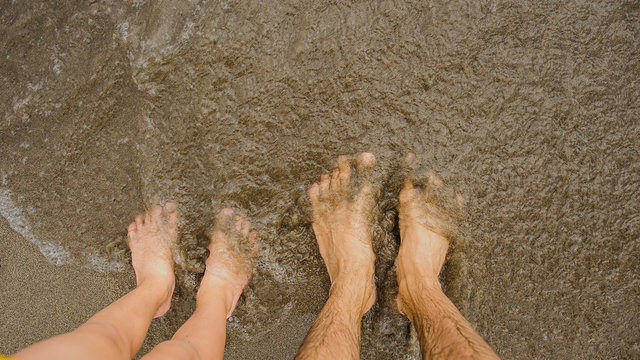 father ans son's legs in the sand at the seaside
