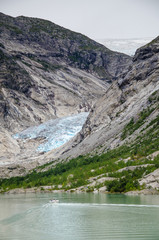 Distance view of the Nigardsbreen glacier with boat on the lake in the foreground