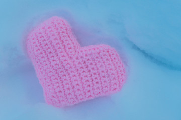 Pink knitted heart on the snow