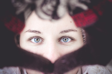 The girl looks with her beautiful eyes through the heart from her hands