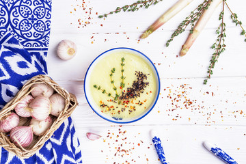 Homemade cream soup with white asparagus, thyme, black sesame and garlic on white background
