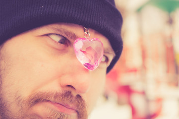 Cheerful man grimaces with a toy heart