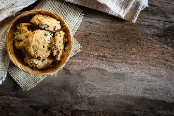 Cookies in weave bowl on rustic wooden table, Top view.
