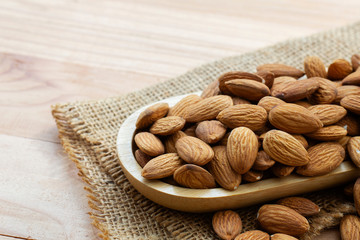almond nuts on wooden plate.