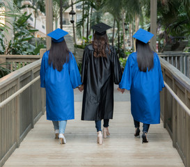 Three friends walking in graduation cap and gown