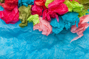 Crumpled colorful tissue paper on a blue tissue paper background 