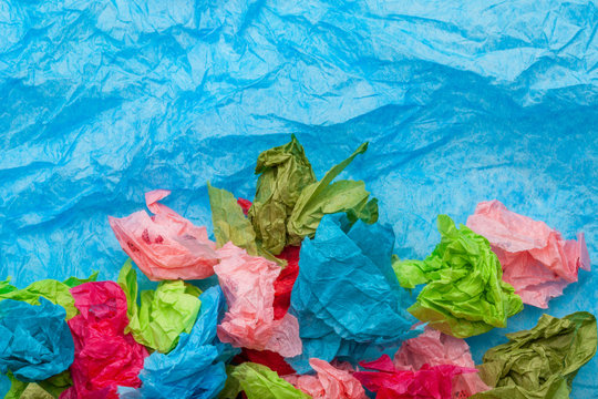 Crumpled colorful tissue paper on a blue tissue paper background 