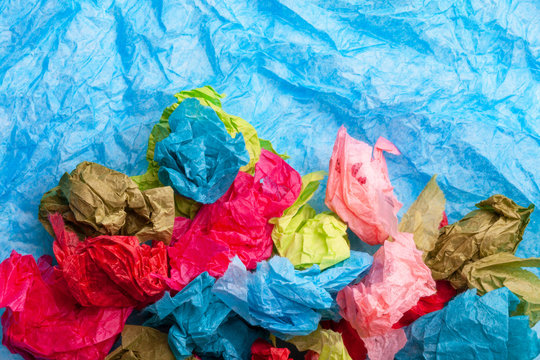 Crumpled colorful tissue paper on a blue tissue paper background 