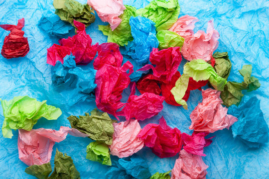 Crumpled colorful tissue paper on a blue tissue paper background 