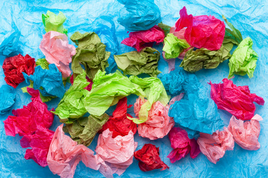Crumpled colorful tissue paper on a blue tissue paper background 