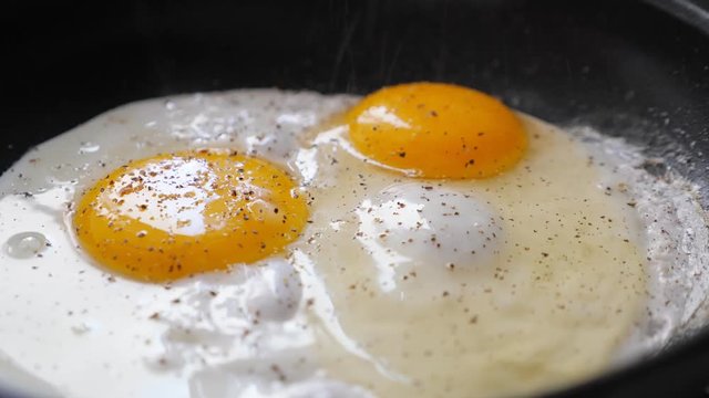 Cooking fried eggs on frying pan, closeup