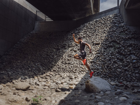 Side view of athlete jumping over rock
