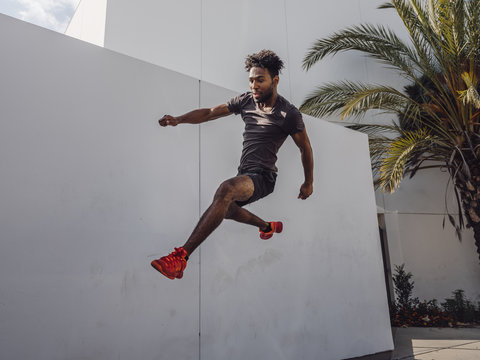 Young male athlete jumping near wall