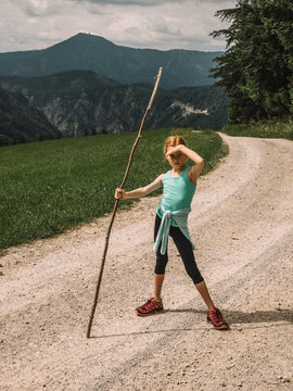 Portrait of girl with stick standing on trail