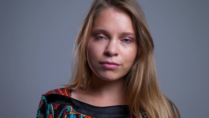 Closeup portrait of charming young caucasian female looking at camera posing and tossing her hair
