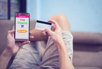 online shopping concept - young man using smartphone shopping in website market online and hands holding credit card