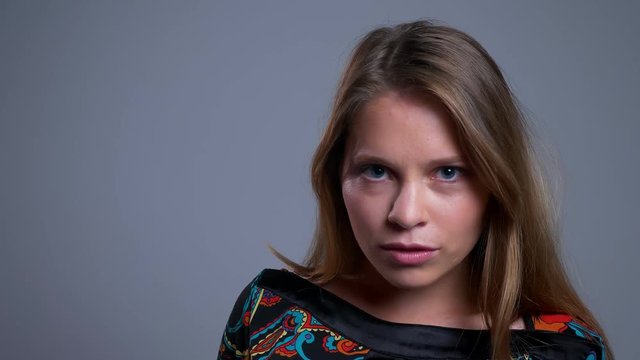 Closeup portrait of seductive young caucasian female looking straight at camera and posing