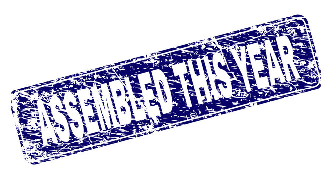 ASSEMBLED THIS YEAR stamp seal print with distress texture. Seal shape is a rounded rectangle with frame. Blue vector rubber print of ASSEMBLED THIS YEAR caption with dust texture.