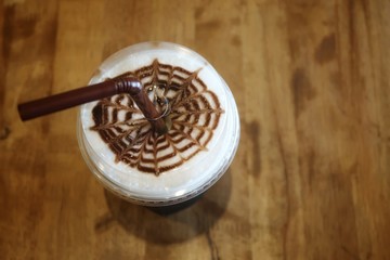 Top view of ice coffee with Latte art in flower or spider web shape on dark table background in vignette warm color tone. Relaxing & refreshing time or coffee & tea break during work day, copy space