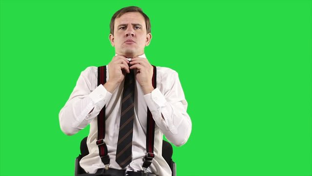 Portrait of modern young businessman. Confident businessman in white shirt straightens his tie on green background. Man been fixing himself up before work.