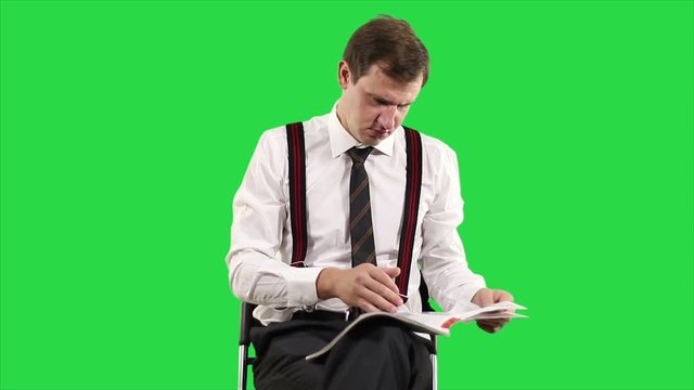 Portrait of modern young business man on green screen.  Successful businessman in white shirt reading a magazine on his own time.