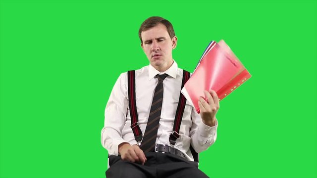 Tired, sleepy businessman, yawning and falling asleep at work in office, feels not healthy cooling herself with hand fan from magazines on green background.