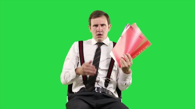 Tired, sleepy businessman, yawning and falling asleep at work in office, feels not healthy cooling herself with hand fan from magazines on green background.