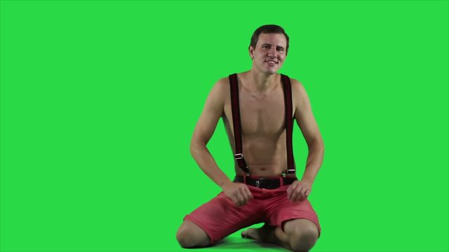 Young man with a beautiful muscular body against a green screen.