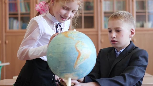 Children at elementary school. Children in geography lesson at school. Pupils view the globe in an elementary school class.